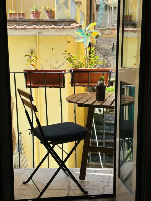 Il balcone visto dalla portafinestra, con sedia e piante