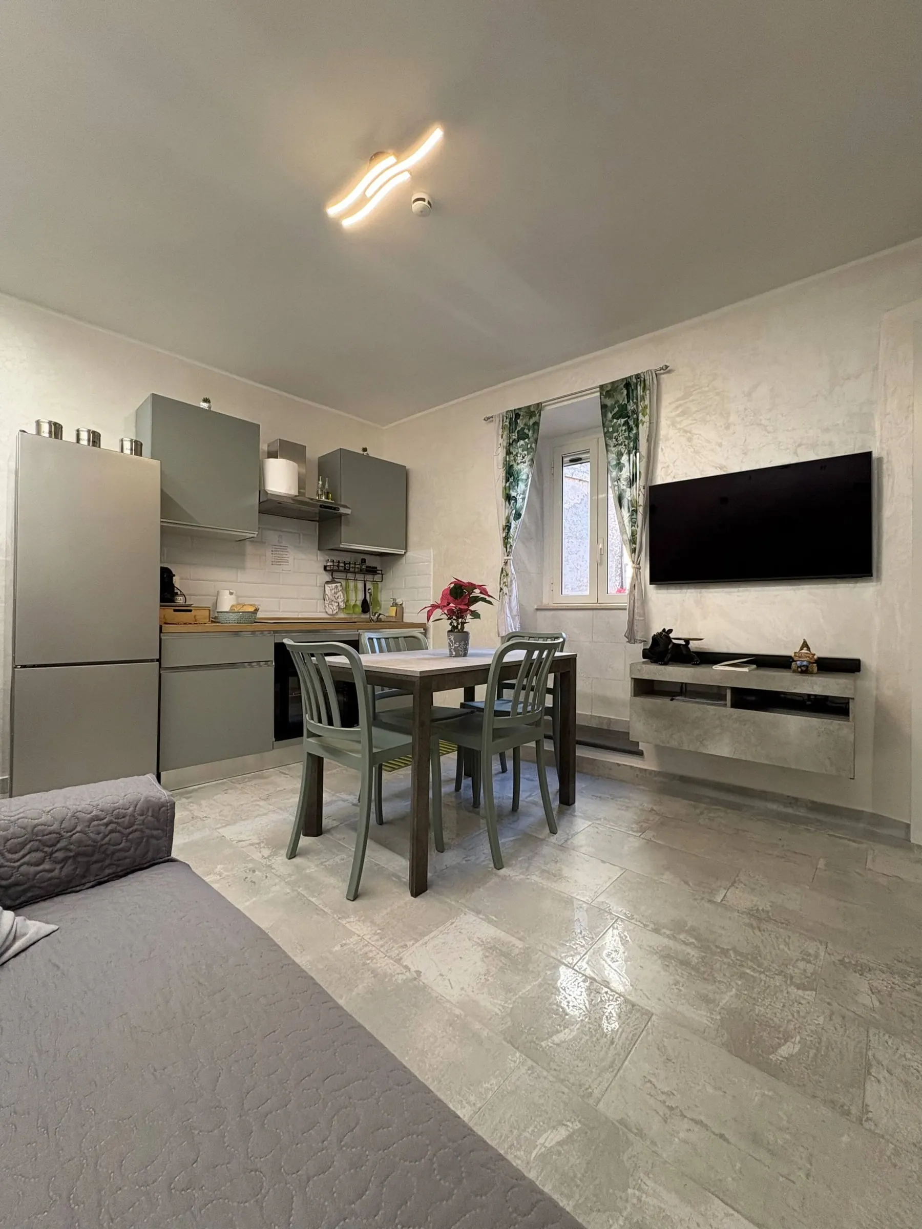 Soggiorno e cucina in un unico ambiente, con tavolo da pranzo e smart TV
